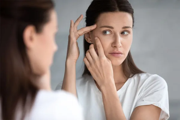 Acne-Scars-Specialist A woman looks at acne in a mirror. Get RF microneedling for acne scar removal from Brandi Terra, NP at Oak & Stone Wellness in East San Diego.