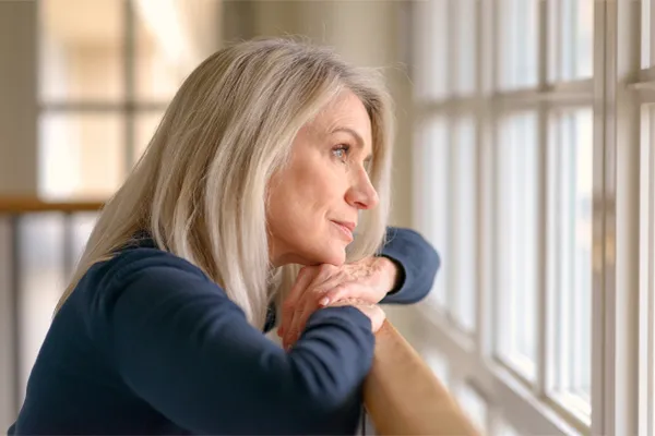 Brain-Fog-Clinic A thoughtful woman gazes out a window, symbolizing the mental fatigue and distraction often associated with brain fog. Get root-cause brain fog treatment by Brandi Terra, NP at Oak & Stone Wellness in East San Diego.