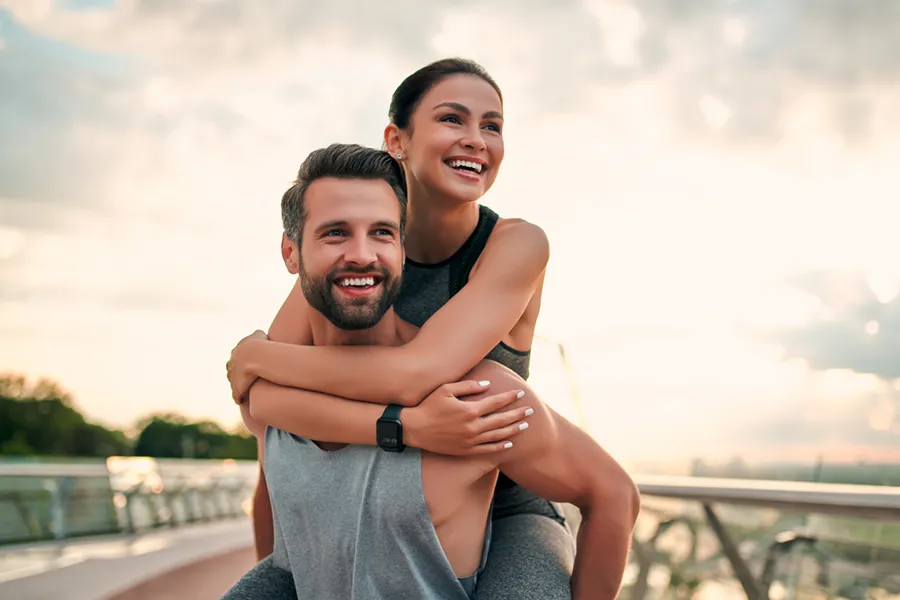 Evolve-Body-Contouring-Clinic A couple embrace on a running track at sunset. Get Evolve body contouring treatment from Brandi Terra, NP at Oak & Stone Wellness in East San Diego.