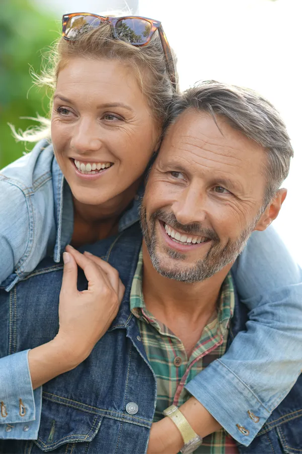 Hypogonadism-Treatment A couple in denim jackets embrace playfully outdoors. Get hypogonadism treatment from Brandi Terra, NP at Oak & Stone Wellness in East San Diego.