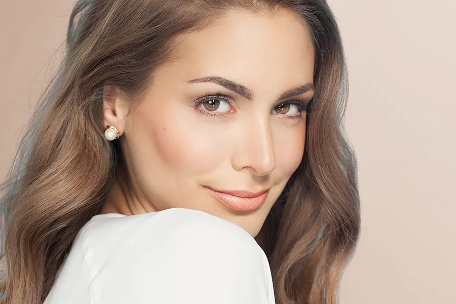 Jueveau-Facial-Injections-Clinic A woman with long brown hair and radiant skin. Get Jueveau facial injections from Brandi Terra, NP at Oak & Stone Wellness in East San Diego.