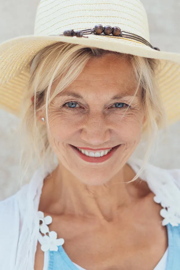 Menopause-Treatment A beautiful, smiling older woman with blonde hair and a sunhat, happy with menopause treatment from Brandi Terra, NP at Oak & Stone Wellness in East San Diego.