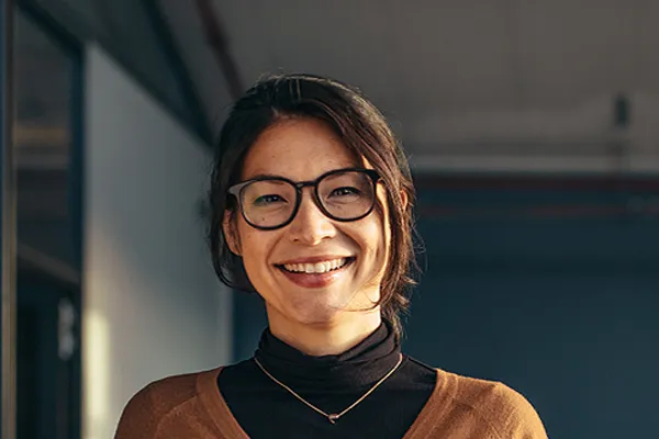 Metabolic-Syndrome-Clinic A brunette woman with glasses smiles in a gray-blue walled office. Get metabolic syndrome from Brandi Terra, NP at Oak & Stone Wellness in East San Diego.