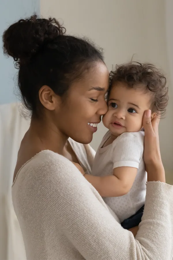 Postpartum-Hormone-Imbalance-Treatment A black woman happily touches her forehead to her infant's head. Get treatment for postpartum hormone imbalance from Brandi Terra, NP at Oak & Stone Wellness in East San Diego.